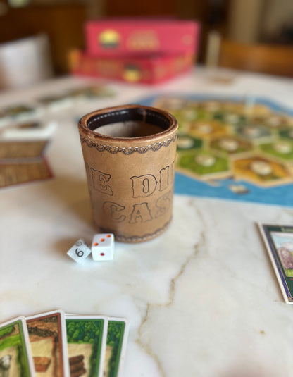 handmade leather dice cup "the die is cast" in front of catan